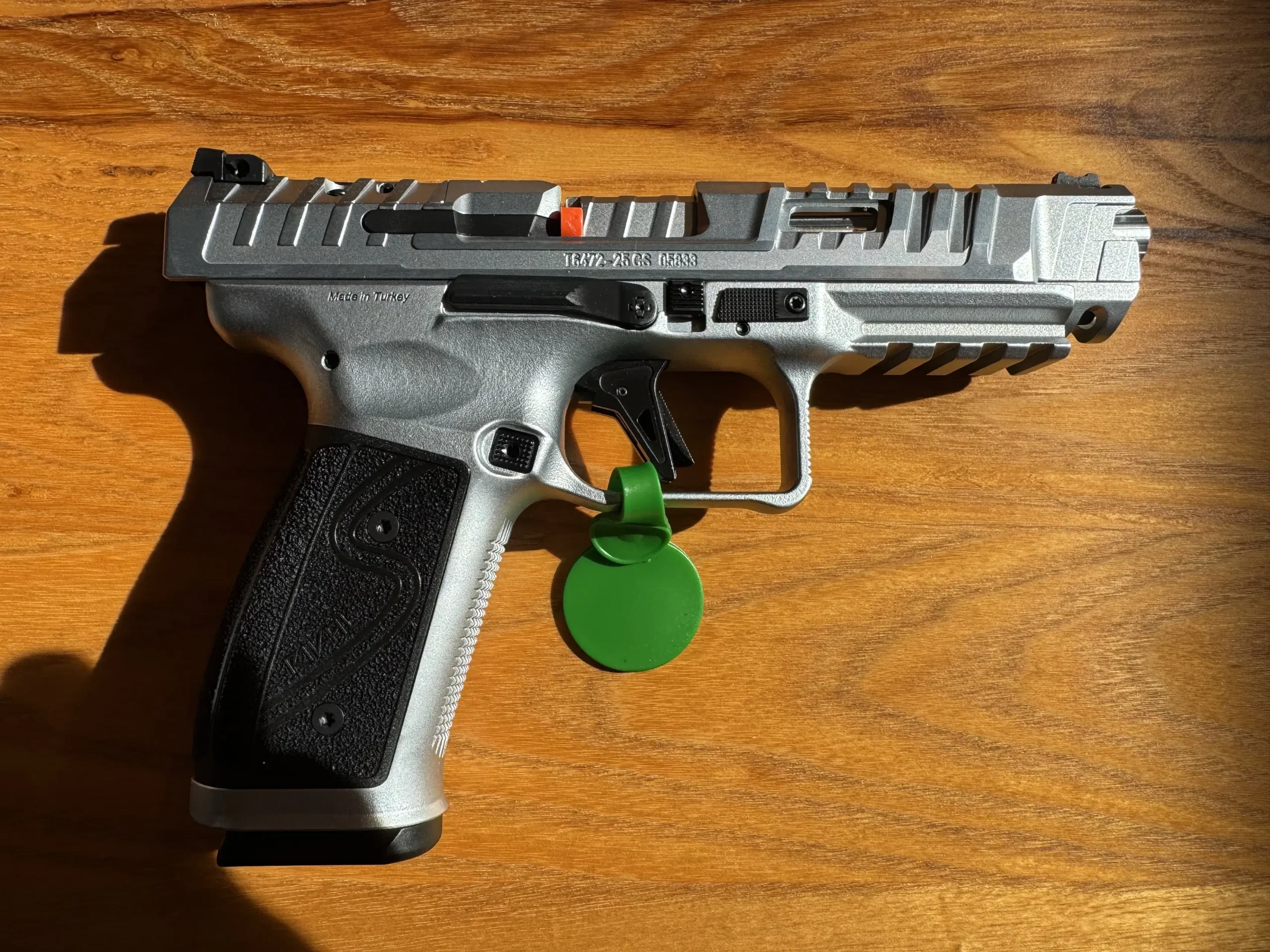 Canik SFx Rival-S 9mm competition pistol with silver steel frame, optic-ready slide, aggressive serrations, and orange fiber optic front sight.